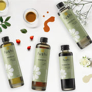 Fushi oil bottles on a white background with flowers and leaves.