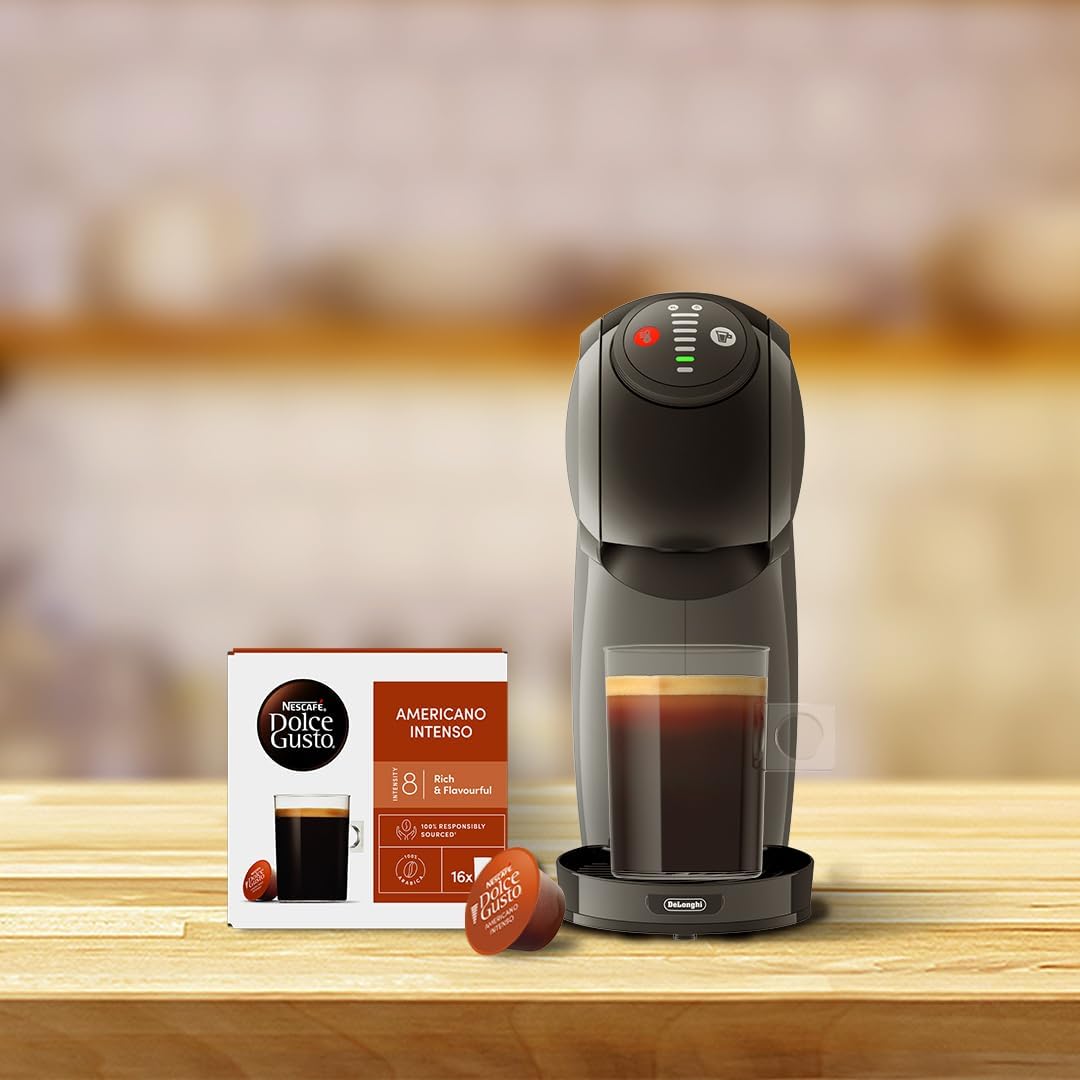 A large mug of black coffee next to a Dolce Gusto machine and a pod.